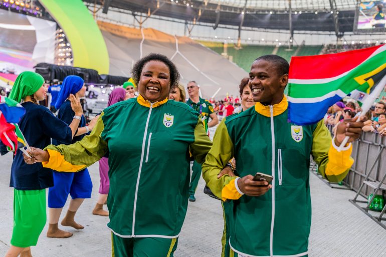 35827070004_2ef8890a66_o Photo of South African athletes walking and smiling while waving flags.