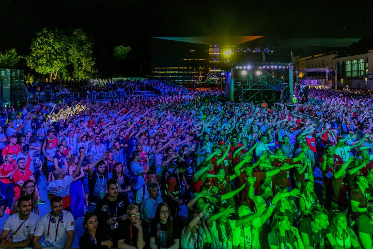 Photo of crowd of people at night with arms raised